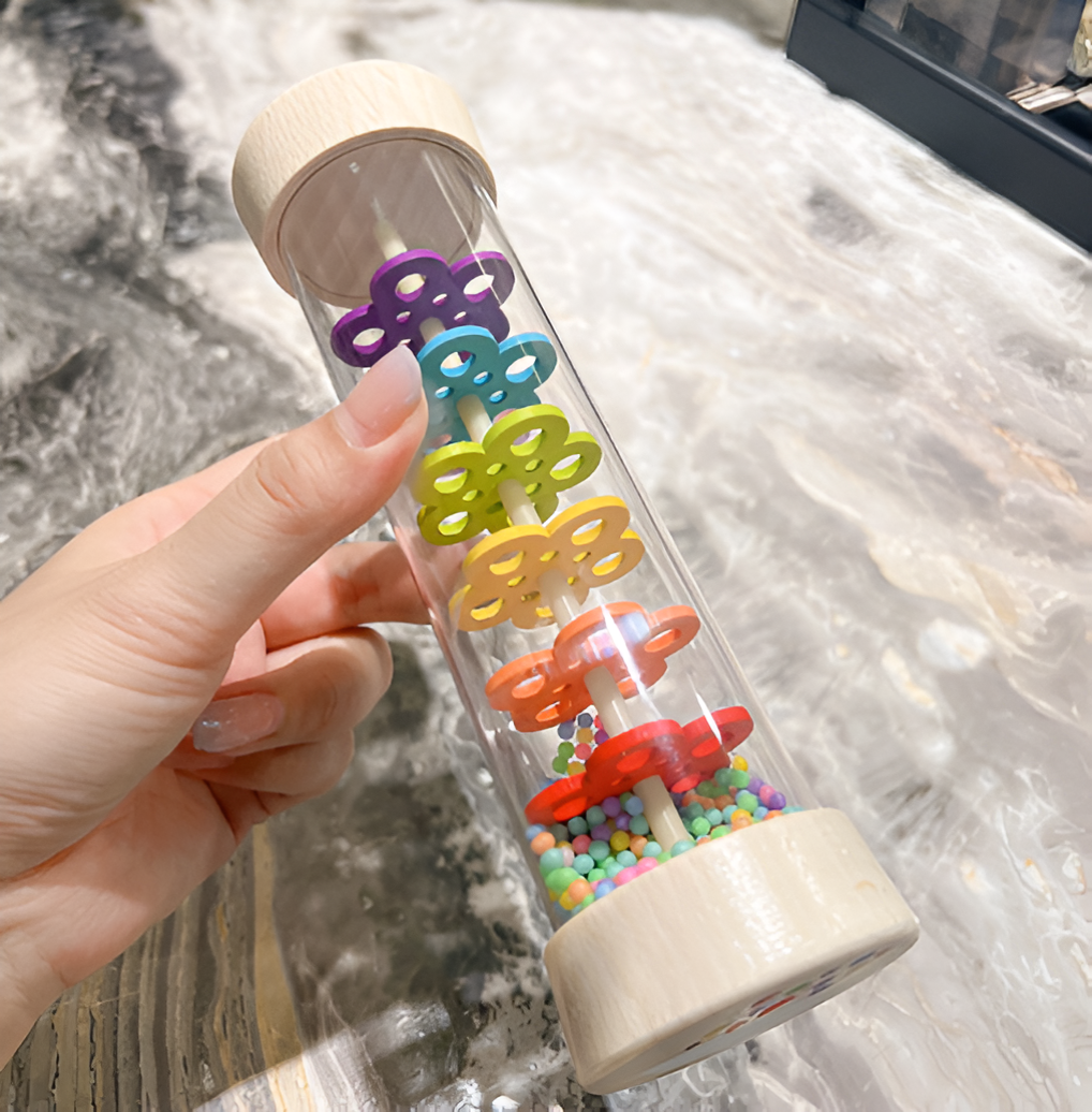 Hand holding a Montessori Wooden Toddler Rattle with colorful spinning gears, designed to enhance sensory development and fine motor skills in toddlers.