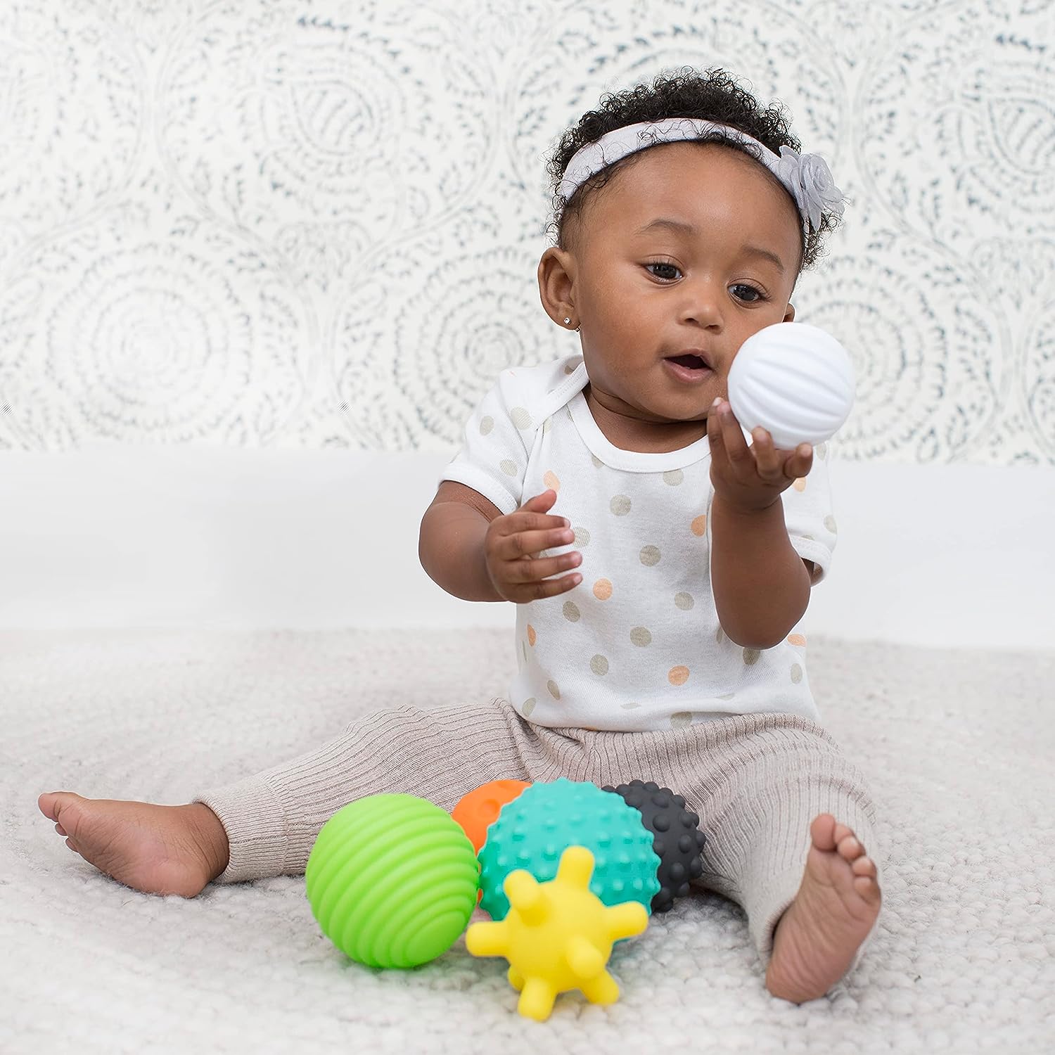 Baby playing with colorful Montessori Sensory Balls (6 Pack), designed to stimulate tactile exploration and enhance sensory development.