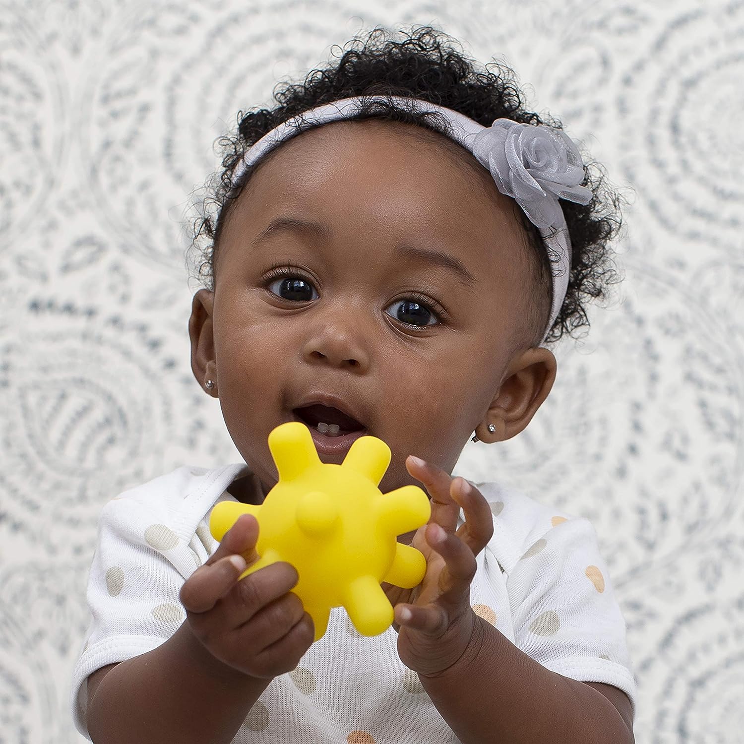 Baby holding yellow sensory ball from Sensory Balls 6 Pack for Montessori play