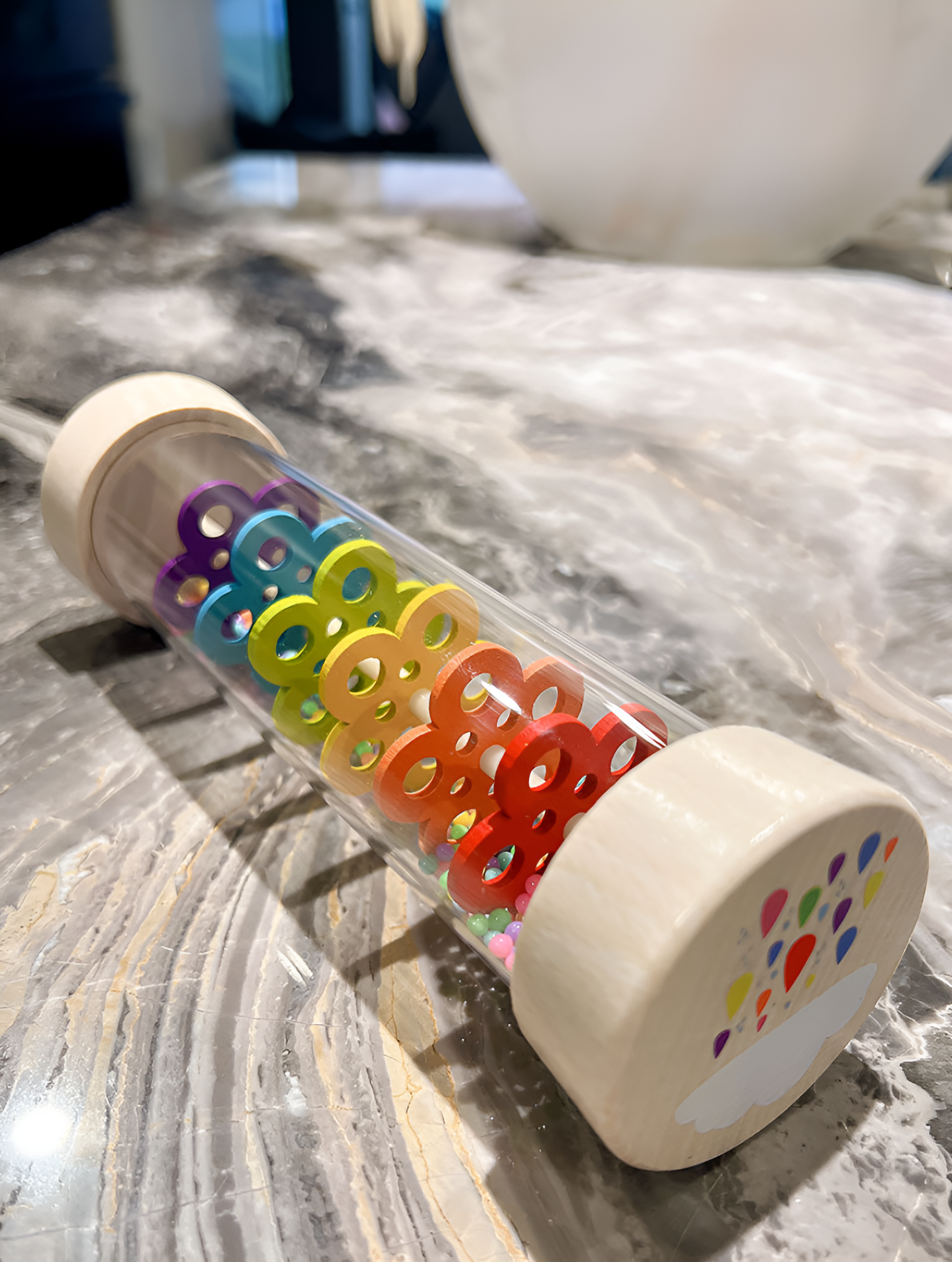 Montessori Wooden Toddler Rattle laying flat, featuring colorful spinning gears that encourage sensory play and fine motor skill development for young children.