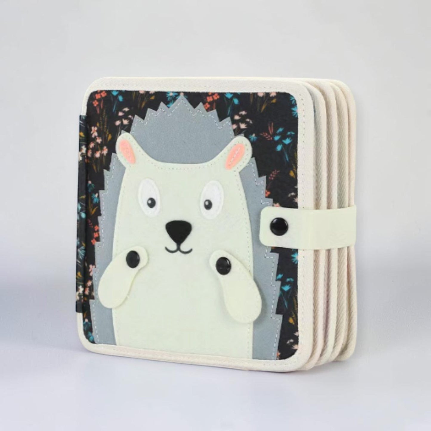 Montessori busy board quiet book hedgehog edition, white and grey felt animal book with cute hedgehog face and snap closure on cover, sensory activity book for toddlers and preschoolers aged 12 months and up.