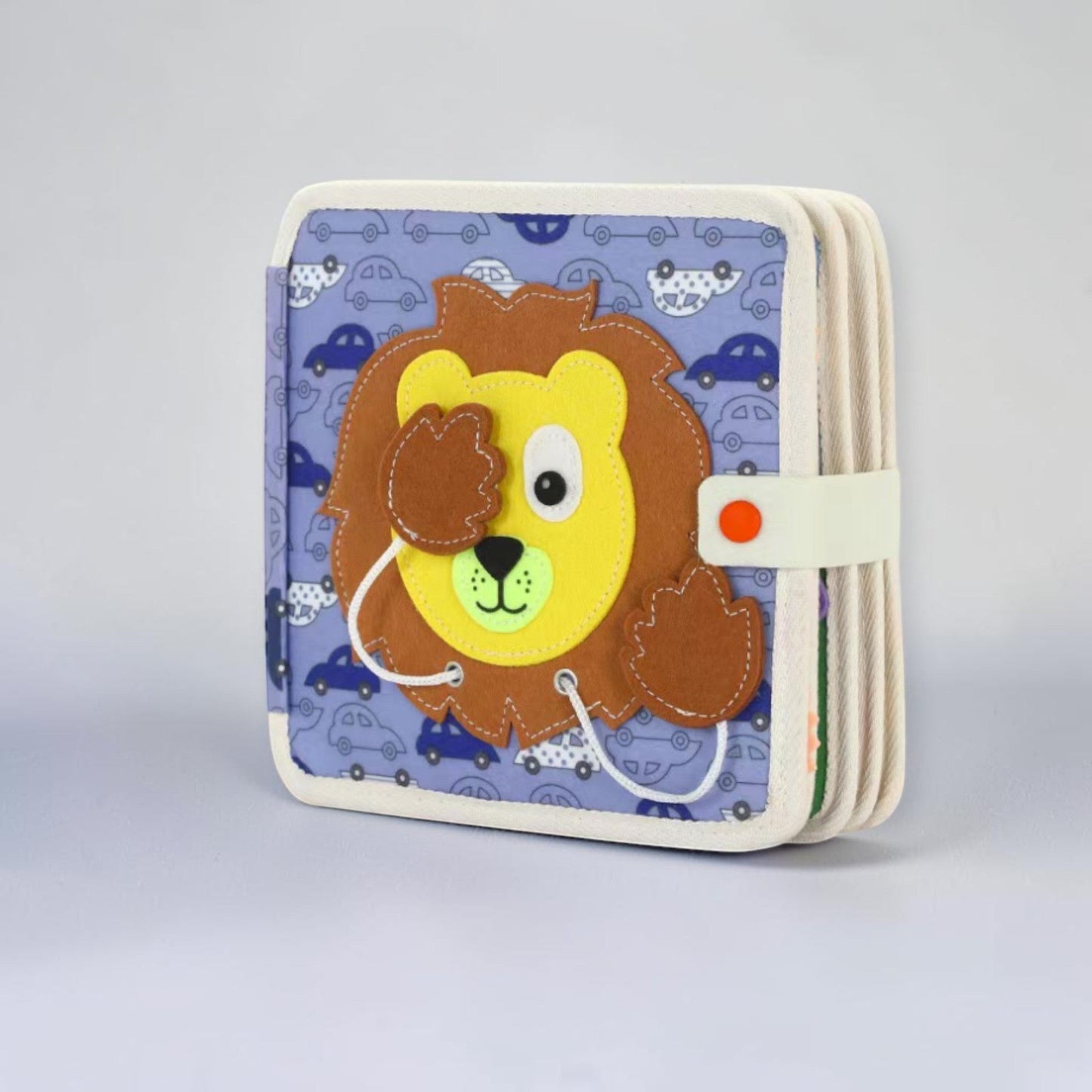 Montessori busy board quiet book lion edition, blue felt animal book with smiling lion face and snap closure on cover, sensory activity book for toddlers and preschoolers aged 12 months and up.
