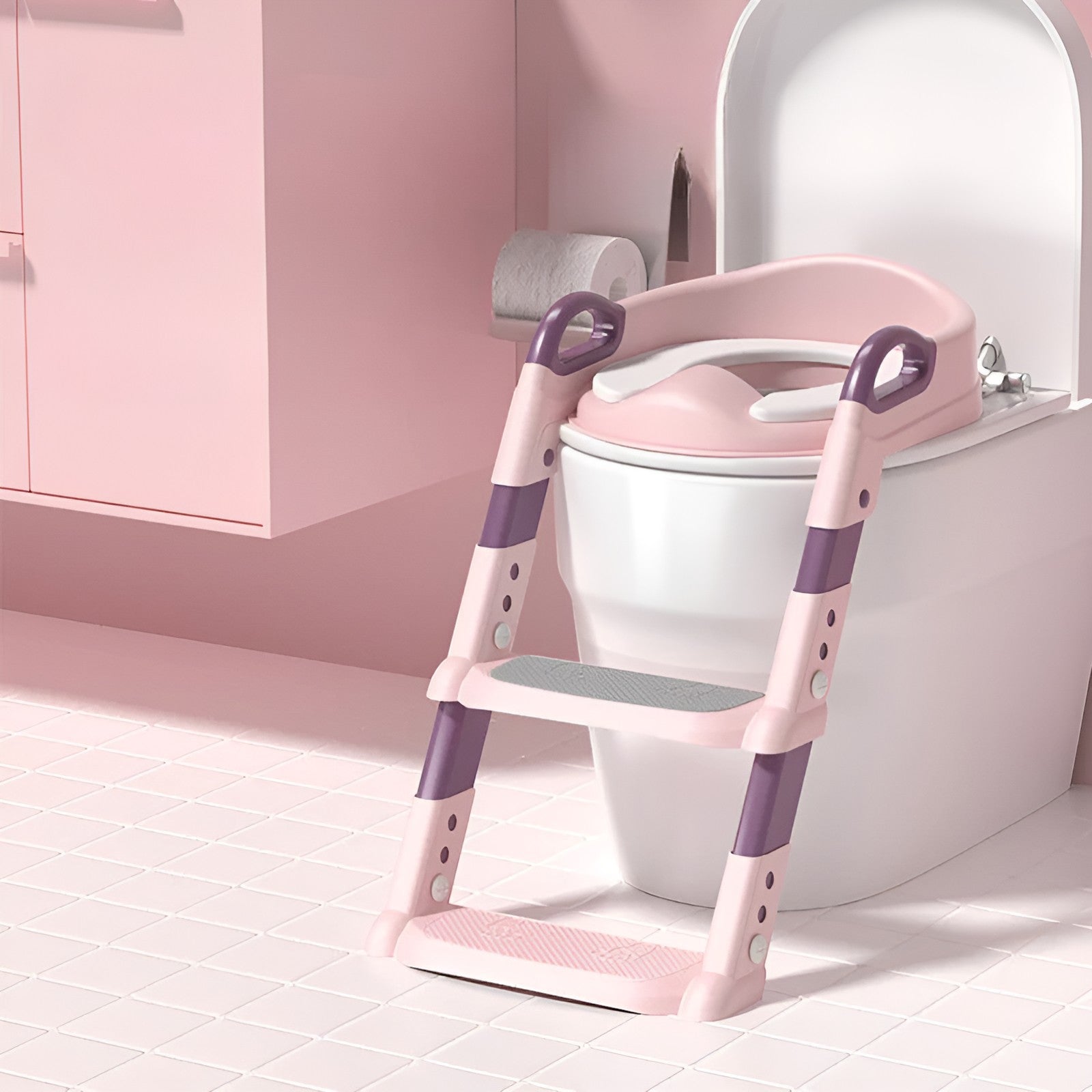 Pink Montessori potty trainer toilet seat with step ladder placed on toilet in pink bathroom, adjustable non-slip toilet training seat with handles and two step ladder for toddlers and young children.